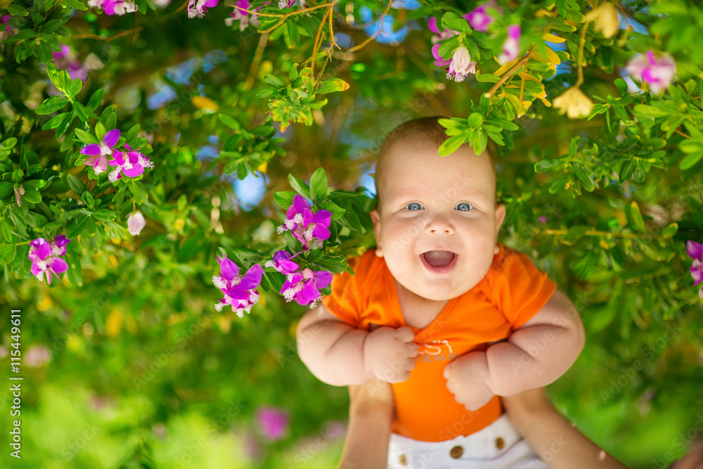 Father keeps his son high up under blooming tree Father keeps his son high up under blooming tree