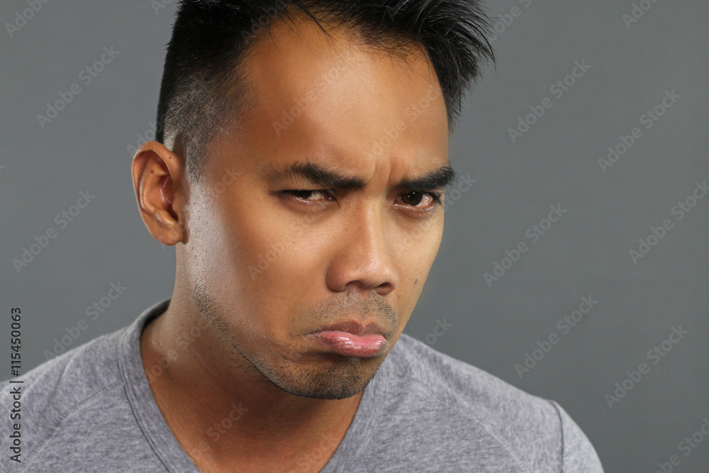 Grumpy young man over a gray background Grumpy young man over a gray background