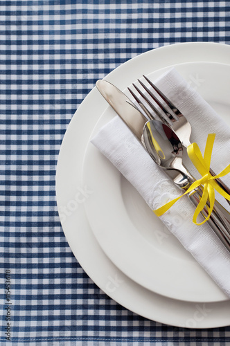 Table setting with blue checkered tablecloth and white napkin