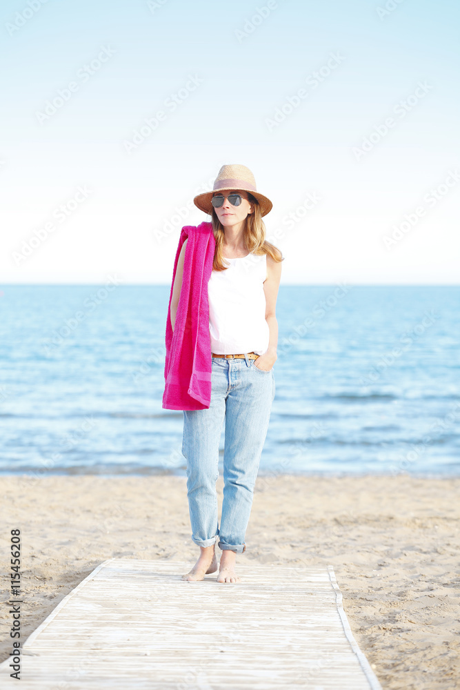 Starting her vacation on the seaside. Mature woman walking on the beach.