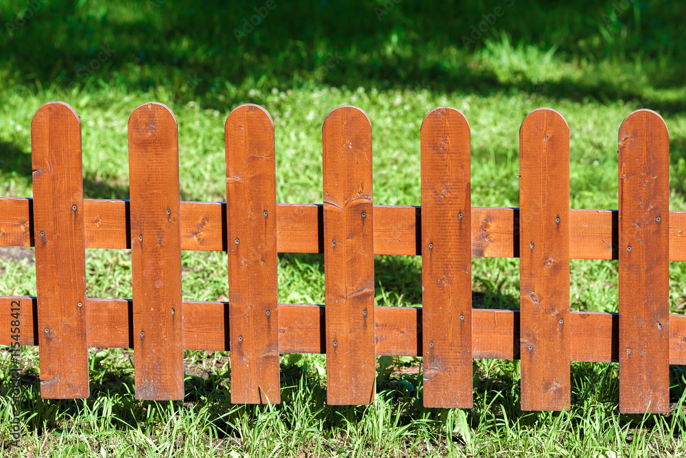 Wooden fence on green grass under the sun