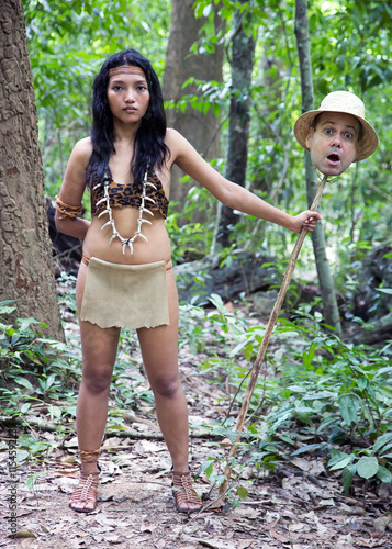 woman in native costume standing with head of travelers impaled on her spear 