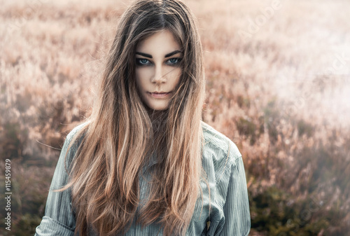 Beautiful and young girl in a man's shirt standing in the field. Fog.
shirt for the girl. Nature. Wind inflates hair.