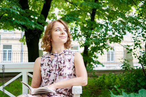 Outdoors portrait of romantic smiling young woman with book