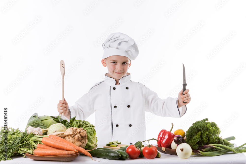 One little boy as chef cook making salad, cooking with vegetable One little boy as chef cook making salad, cooking with vegetable