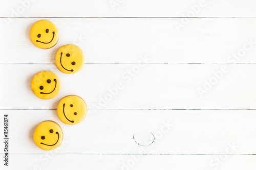 Smiley faces on wooden white background. Food. Glazed cookies. Top view, flat lay