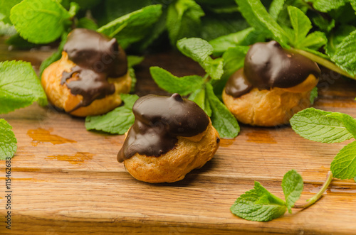 French eclairs covered with chocolade on wooden board photo