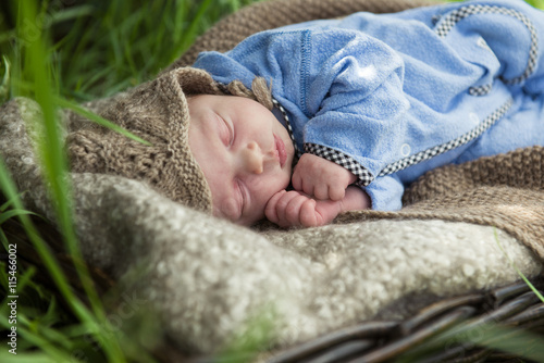 newborn baby in blue suit sleeping in the garden