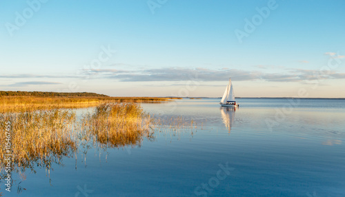 Sailing boat on a calm lake with reflection photo