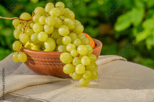 Fresh juicy fruit in a clay bowl on natural background. Grapes.