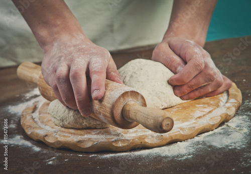 Making dough by mens hands on wooden table background