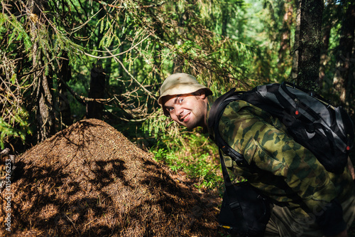 the man naturalist has found a big ant hill in forest and shows it to us photo