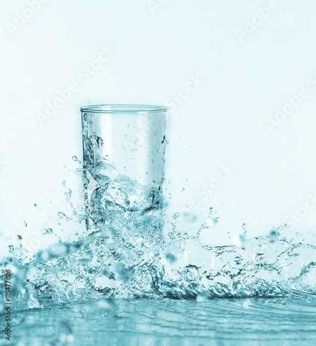 Pouring water into glass on light background