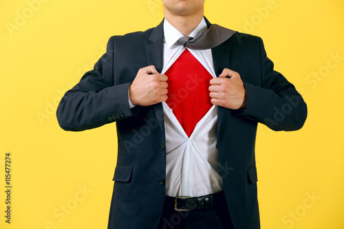 Young businessman super hero on yellow background