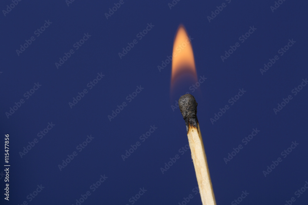 Burning match stick against blue background Burning match stick against blue background