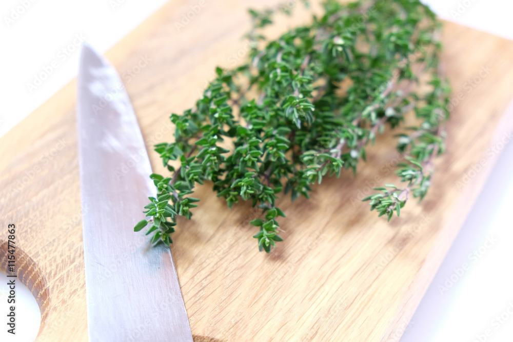 High key image of organic thyme fresh herb on a wooden chopping board with a knife blade. Very shallow depth of field. High key image of organic thyme fresh herb on a wooden chopping board with a knife blade. Very shallow depth of field.