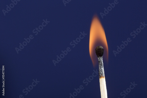Burning match stick against blue background