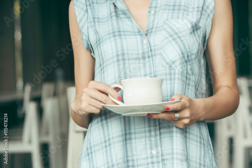 Close up image of female hands holding white ceramic cup