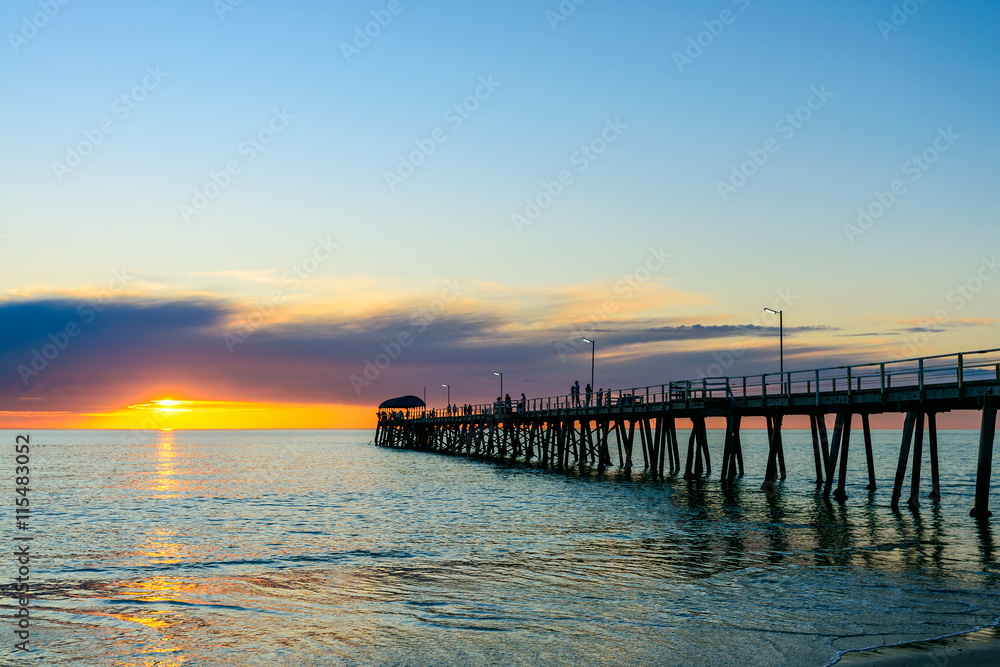 People wailking along jetty at sunset