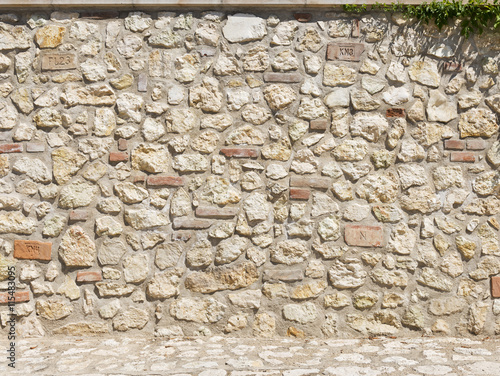 Picturesque stone wall in a bright sunny day as background