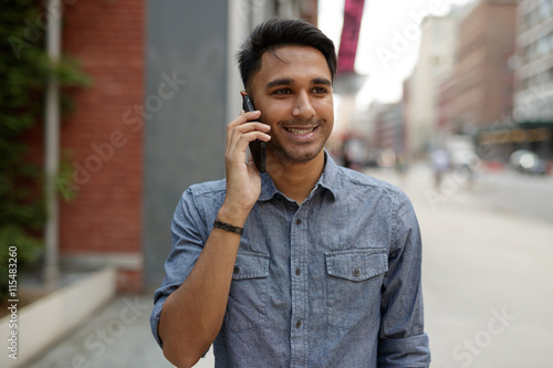 Young Indian man in city talking on cell phone