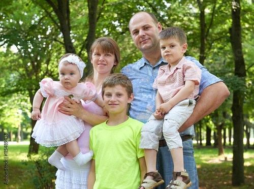happy family portrait on outdoor  group of five people posing in city park  summer season  child and parent