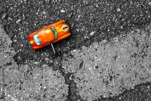 Obraz na plátně Orange clockwork toy car on asphalt background