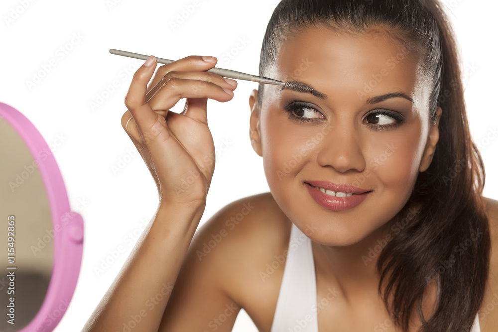 A young Indian woman shaping her eyebrows with a brush