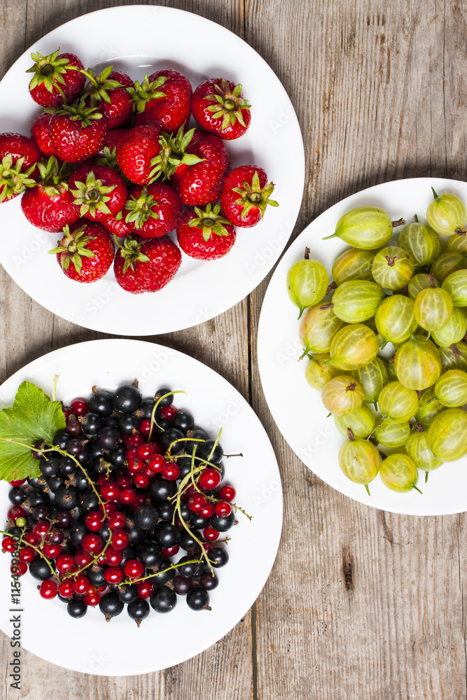 Summer berries on a wooden table.Goosbery, strawberry,black, red Summer berries on a wooden table.Goosbery, strawberry,black, red