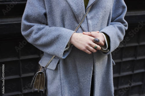 Midsection of woman wearing grey overcoat with hands clasped