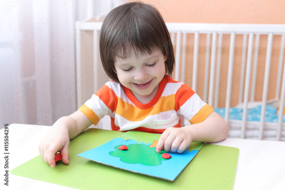 Little 3 years boy modelling apple tree of playdough