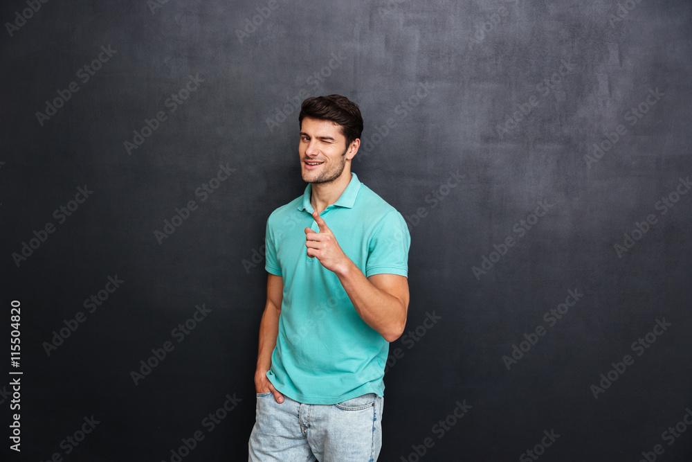 Handsome young man pointing at camera over black background