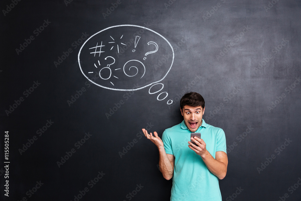 Crazy hysterical man using smartphone and screaming over chalkboard background