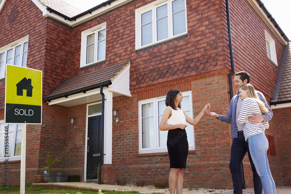 Obraz premium Young Couple Collecting Keys To New Home From Realtor