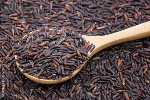 Closeup of black rice called rice berry rice with wooden spoon.