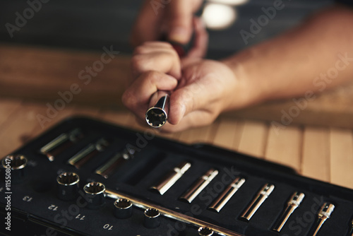 Close-up of mechanic hands changing socket wrench over toolbox. Concept of repair and diy.  photo
