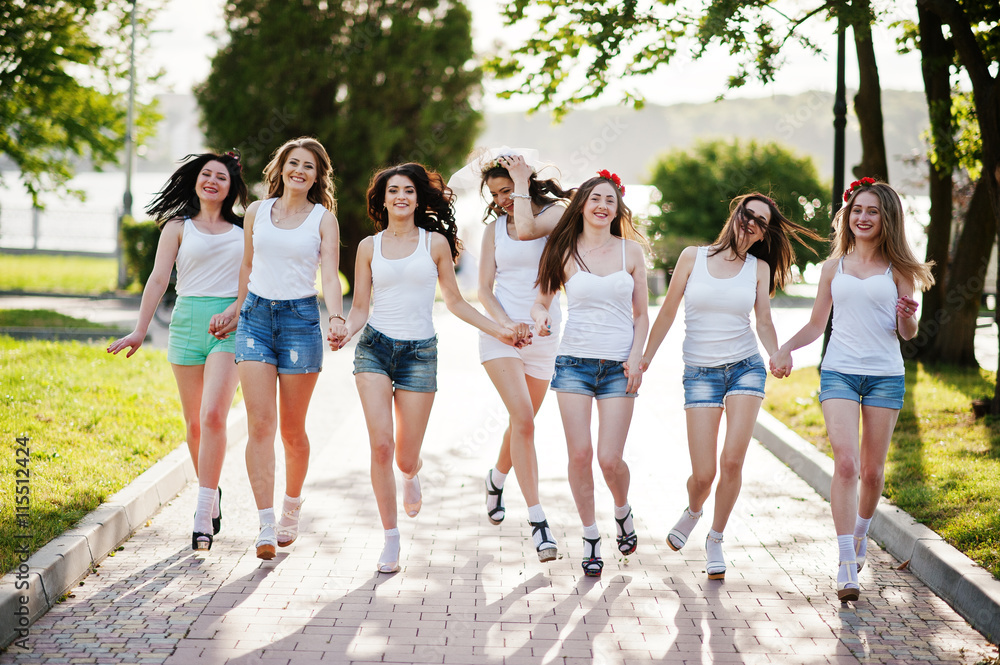 Seven happy and sexy girls on short shorts and white shirts runn