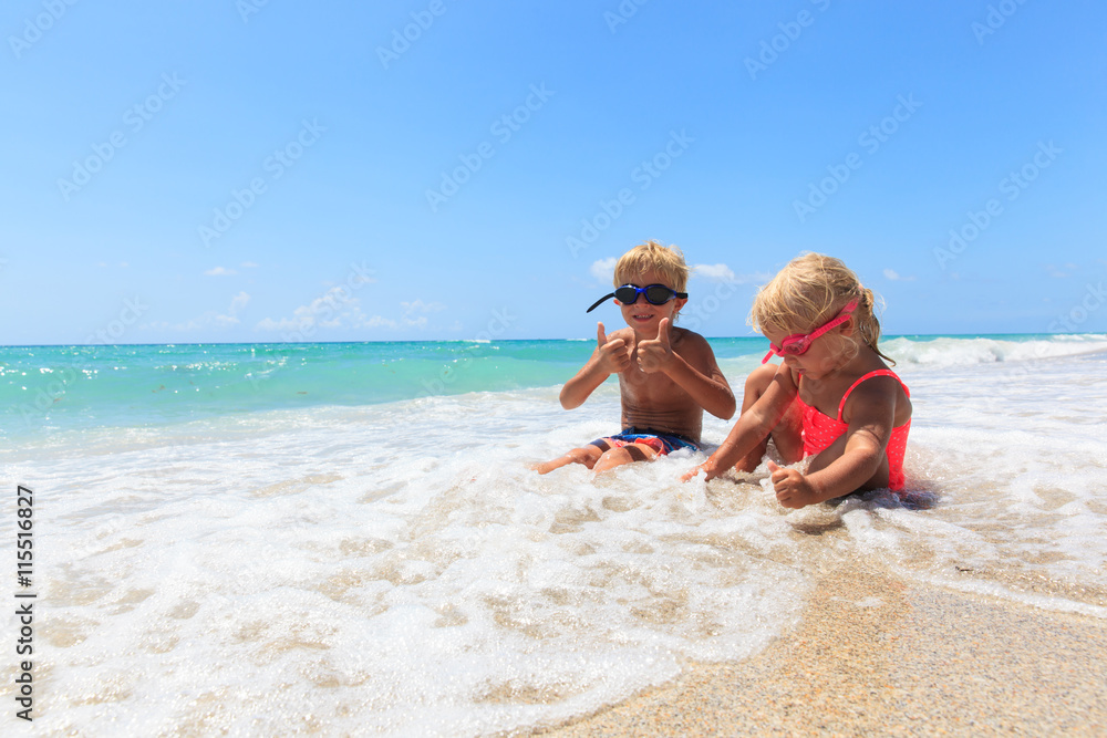 happy little boy and girl play with water on beach