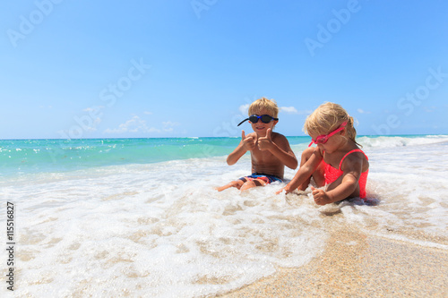 happy little boy and girl play with water on beach