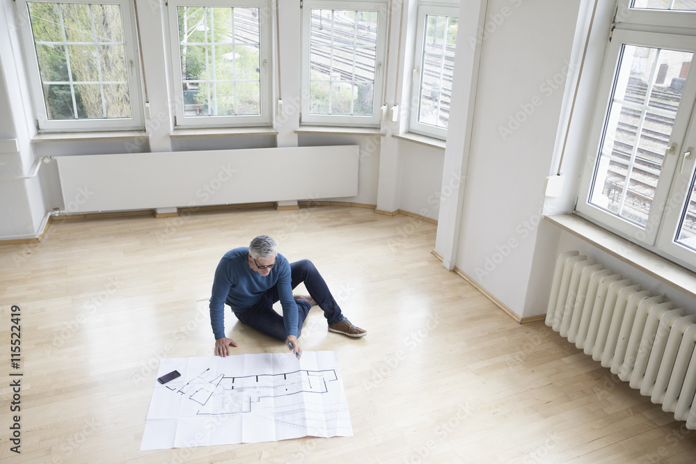 Man looking at construction plan in empty apartment Man looking at construction plan in empty apartment