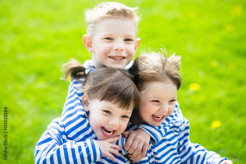 Three adorable little kids in striped T-shirts outdoors at warm summer day Three adorable little kids in striped T-shirts outdoors at warm summer day