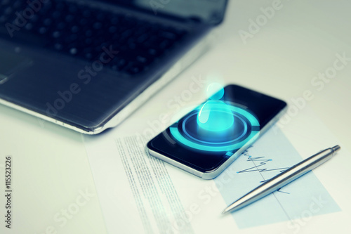 close up of smartphone, laptop and pen on table