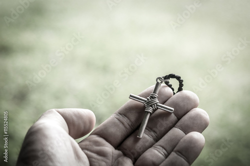 Hand with a rosary against gray background, religious concept.process in vintage color tone