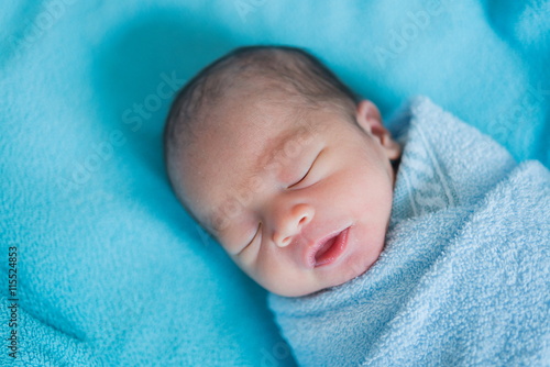 Newborn baby Asia while sleeping covered with blue cloth