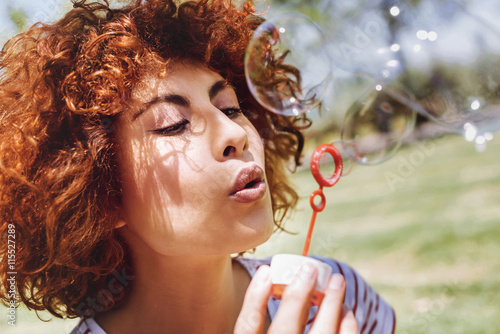 Beautiful young woman blowing bubbles in a park photo