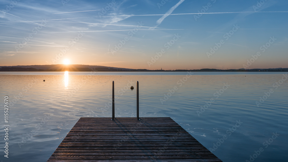 Jump. Relaxing quiet evening on the lake. Setting sun is reflected in water. Switzerland.