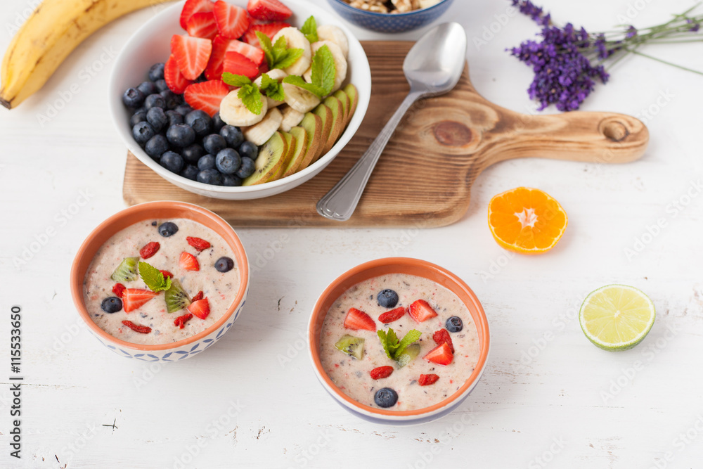 Vegan fruit and berry smoothie breakfast, topped with blueberries, strawberries and mint, seved with fruits, berries and nuts, selective focus Vegan fruit and berry smoothie breakfast, topped with blueberries, strawberries and mint, seved with fruits, berries and nuts, selective focus