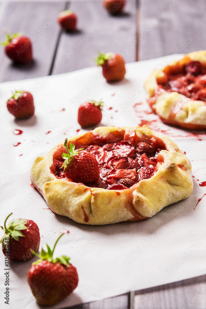 Rustic Tarts with strawberries on a white paper for baking Rustic Tarts with strawberries on a white paper for baking