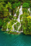 Picturesque waterfalls, surrounded by green trees and emerald lake, Plitvice Lakes National Park, Croatia, vertical nature background