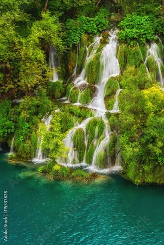 Picturesque waterfalls  surrounded by green trees and emerald lake  Plitvice Lakes National Park  Croatia  vertical nature background